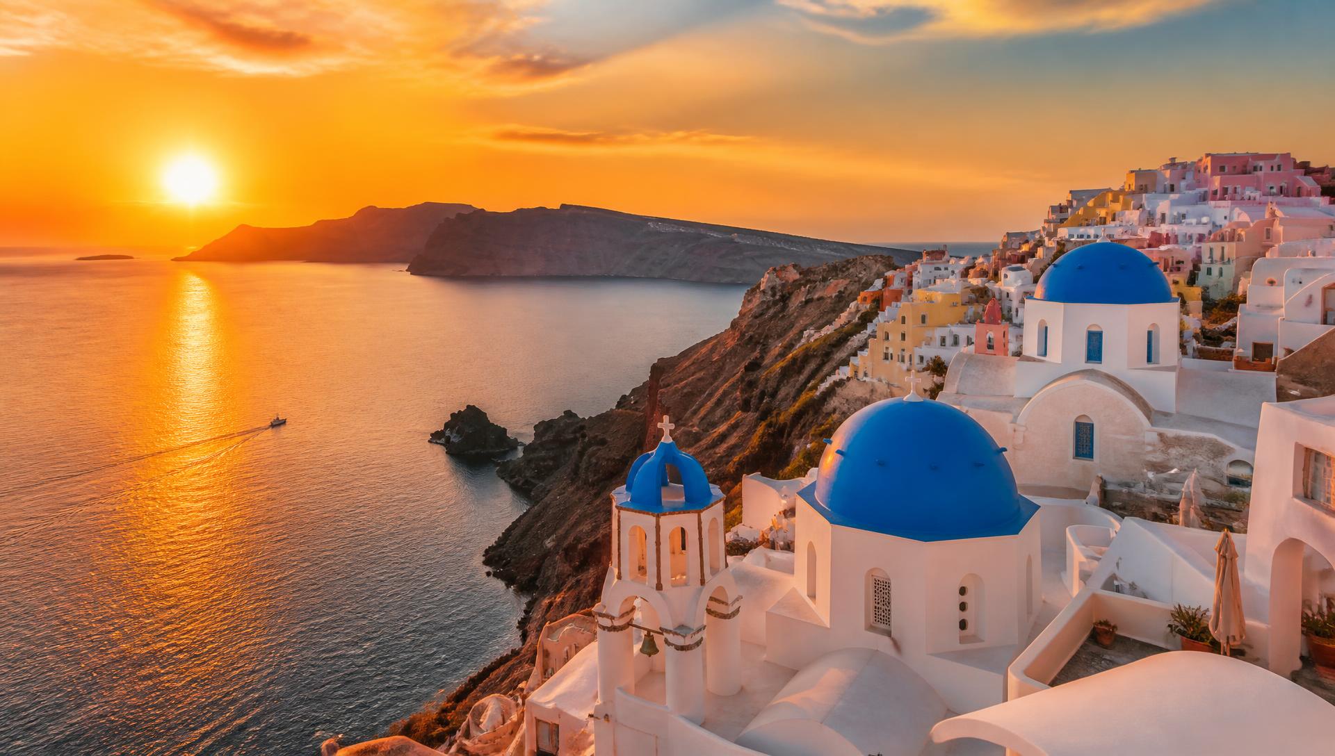 Golden sunset over the blue-domed churches of Oia, Santorini, above the Aegean caldera