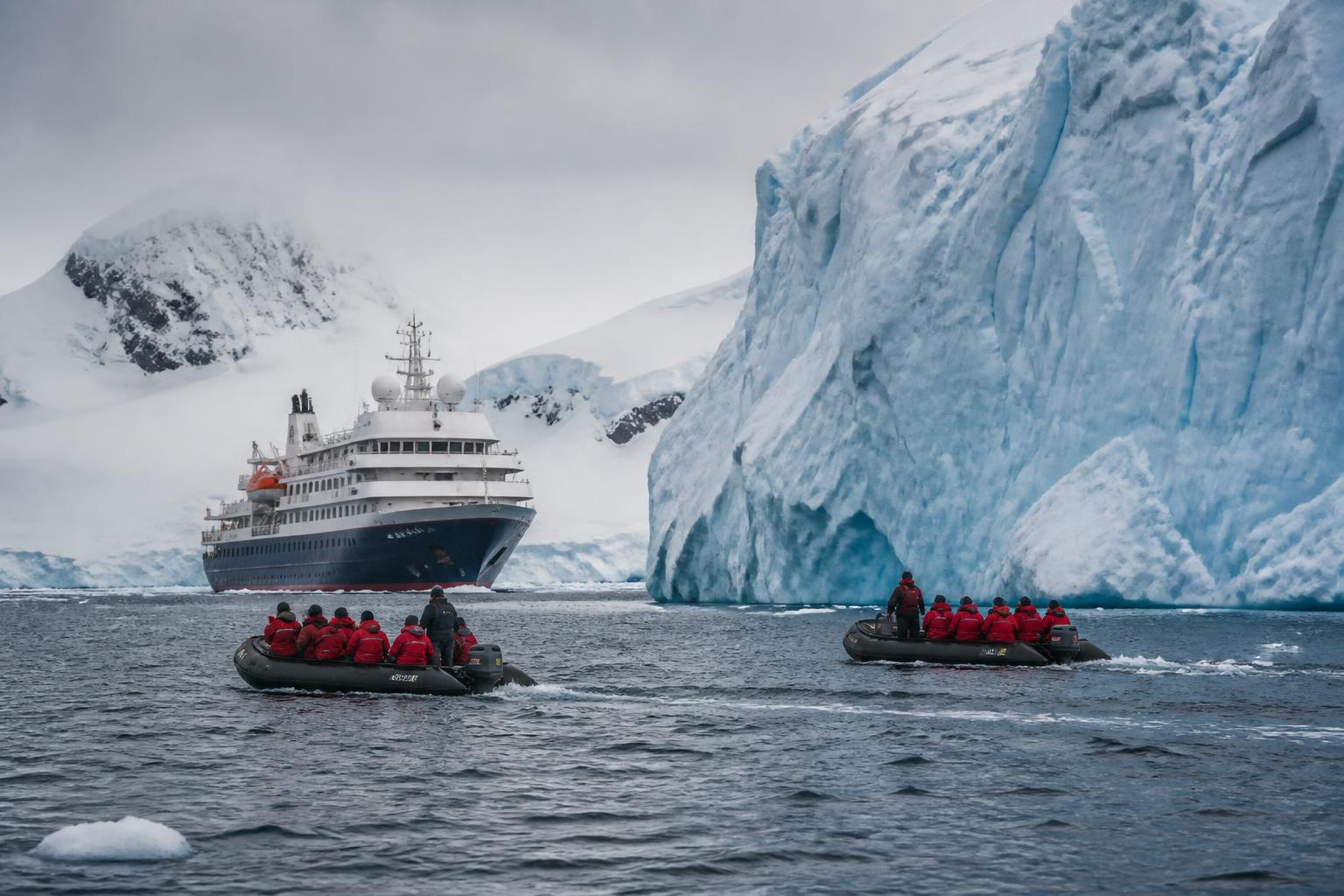 Expedition ship among Antarctic icebergs with Zodiac boats and penguins on the ice